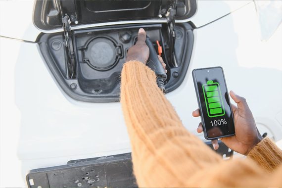 1-perto-homem-afro-americano-conectando-o-cabo-de-carregamento-ao-carro-eletrico-jovem-macho-em-pe-perto-de-seu-automovel-moderno-com-mala-de-couro-na-mao